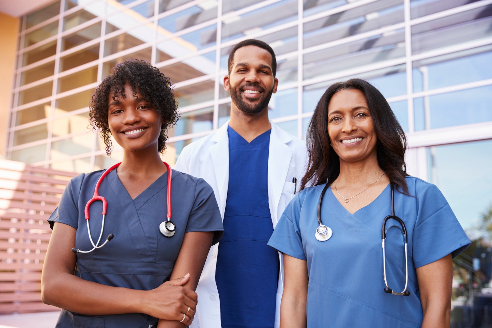 three healthcare colleagues standing outside modern hospital
